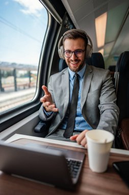 Hızlı trenle seyahat ederken dizüstü bilgisayarını kullanan orta yaşlı yakışıklı bir iş adamı. Modern ve hızlı seyahat kavramı.
