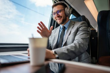 Hızlı trenle seyahat ederken dizüstü bilgisayarını kullanan orta yaşlı yakışıklı bir iş adamı. Modern ve hızlı seyahat kavramı.