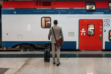Bavullu yakışıklı orta yaşlı işadamı istasyon peronunda duruyor ve hızlı tren ya da metro bekliyor. Modern ve hızlı seyahat kavramı.