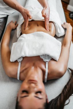 Güzel genç bir kadın aromaterapi ile profesyonel vücut masajı yaptırıyor..