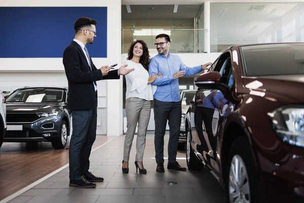 中年夫妇在汽车展示室选择和购买汽车 汽车推销员帮助他们作出正确的决定 — 图库照片