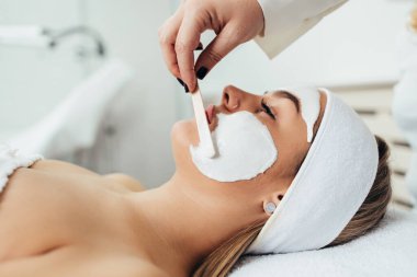 Güzel ve çekici yetişkin kadın maskesiyle profesyonel güzellik tedavisi görüyor..