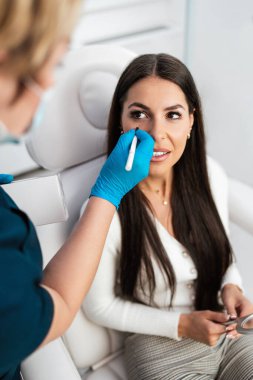 Güzellik kliniğindeki güzel ve mutlu esmer kadın. Kadın doktorla yüz estetiği hakkında konuşuyor..