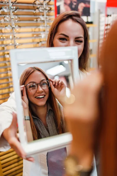 Beautiful Fashionable Redhead Woman Choosing Eyeglasses Frame Modern Optical Store — Fotografia de Stock