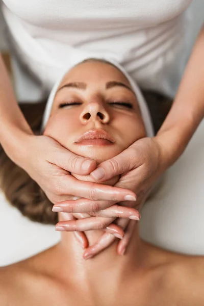Body and neck massage in spa. Professional female beautician doctor with patient in wellness center. Cosmetologist working procedure to beautiful young adult woman in cosmetology cabinet or beauty parlor. Close up shot.