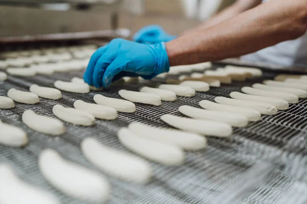 Huge factory line for sweet food and cookies production. Close up shots of worker\'s hand with protective glove doing some selection and product arranging.