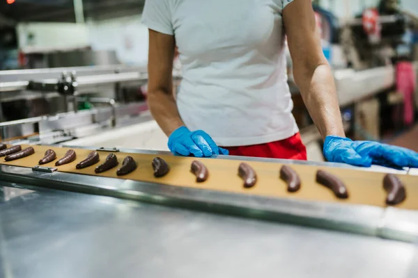 Huge factory line for sweet food and cookies production. Close up shots of worker\'s hand with protective glove doing some selection and product arranging.