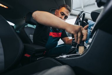 Profesyonel işçi araba temizleme iç ve ön panel, araba temizleme veya valelik konsepti. Seçici odaklanma. Ultra geniş açı..