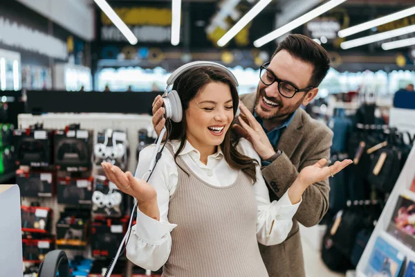 stock image Beautiful and happy middle age couple buying consumer tech products in modern home electronics store. They are choosing high quality hifi audio speakers and audiophiles headphones. 