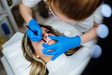 Professional permanent make up procedure. Tattoo lips makeup treatment in modern beauty salon.