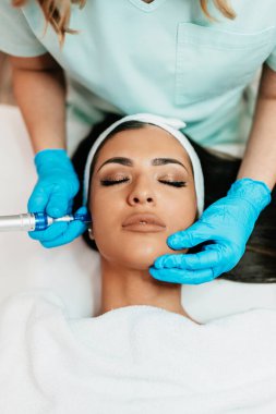 Professional cosmetologist making mesotherapy injection with dermapen on face for effective skin rejuvenation. Modern cosmetology spa treatment.