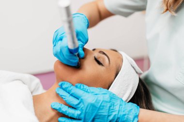 Professional cosmetologist making mesotherapy injection with dermapen on face for effective skin rejuvenation. Modern cosmetology spa treatment.