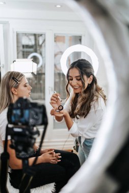 Evden ya da atölyeden güzel makyaj videosu yayınlayan mutlu genç bir kadın. Güzel çevrimiçi içerik kozmetikçisi makyaj yapıyor ve bazı iş araçlarını açıklıyor. Günlük kaydı ve çevrimiçi kanal çalışması. 