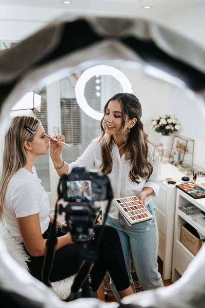 Evden ya da atölyeden güzel makyaj videosu yayınlayan mutlu genç bir kadın. Güzel çevrimiçi içerik kozmetikçisi makyaj yapıyor ve bazı iş araçlarını açıklıyor. Günlük kaydı ve çevrimiçi kanal çalışması. 