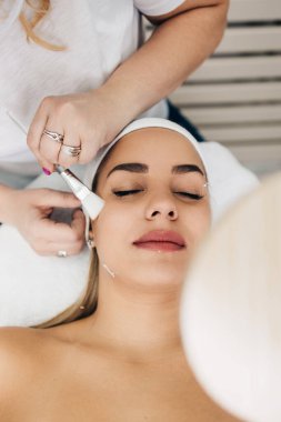 Güzel ve çekici yetişkin kadın maskesiyle profesyonel güzellik tedavisi görüyor..