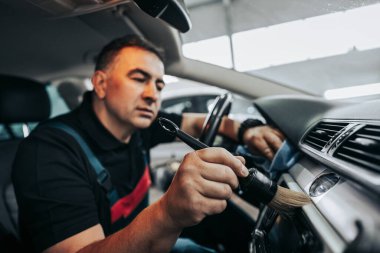 Profesyonel işçi temizleme iç ve ön panel, araba temizleme (veya valelik) konsepti. Seçici odaklanma. Ultra geniş açı..