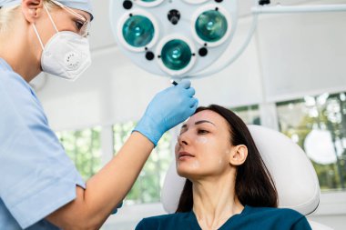 Güzel esmer kadın hasta botulinyum toksin iğneleriyle tıbbi ve güzellik tedavisine hazırlanıyor..