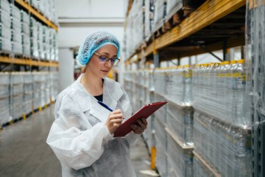 Tıbbi malzeme araştırma ve üretim fabrikasında çalışan ve sevkiyattan önce damıtılmış su dolu kutuları kontrol eden koruyucu işçi. Denetleme kalite kontrolü. Sanayi deposu.