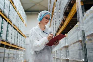 Tıbbi malzeme araştırma ve üretim fabrikasında çalışan ve sevkiyattan önce damıtılmış su dolu kutuları kontrol eden koruyucu işçi. Denetleme kalite kontrolü. Sanayi deposu.