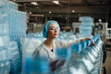 Tıbbi malzeme araştırma ve üretim fabrikasında çalışan ve sevkiyattan önce damıtılmış su kutularını kontrol eden koruyucu işçi. Denetim kalite denetimi. 