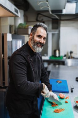 Yakışıklı sakallı profesyonel şef restoran mutfağında çalışıyor. O, balık ve deniz ürünleriyle sağlıklı lezzetli yemekler hazırlar..