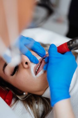 Professional permanent make up procedure. Tattoo lips makeup treatment in modern beauty salon.