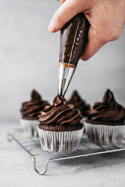 Making and decorating of delicious homemade chocolate cupcakes. Sweet food concept.