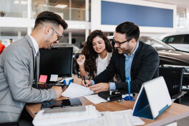 Araba galerisinden araba alan orta yaşlı bir çift. Araba satıcısı doğru karar vermelerine yardımcı oluyor. Adam alıcı sözleşmesi imzalar..