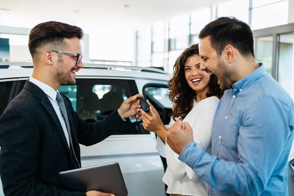 一对中年夫妇在一家汽车经销店买车 卖主把车钥匙给了他们 他们很高兴 — 图库照片