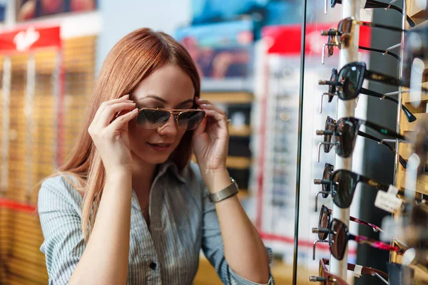 Beautiful Fashionable Redhead Woman Choosing Eyeglasses Frame Modern Optical Store — Foto Stock