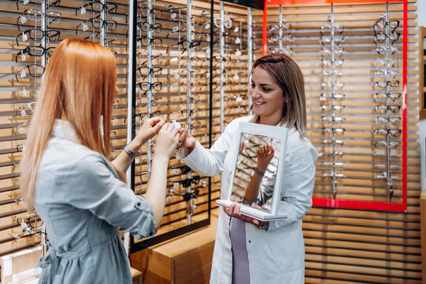 Beautiful Fashionable Redhead Woman Choosing Eyeglasses Frame Modern Optical Store — 스톡 사진