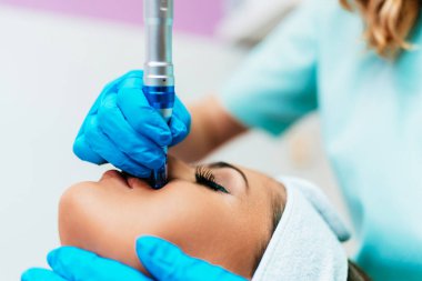 Professional cosmetologist making mesotherapy injection with dermapen on face for effective skin rejuvenation. Modern cosmetology spa treatment.