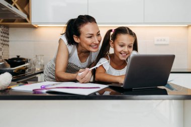 Genç bir anne, virüs salgını sırasında ya da karantinada kızına e-öğrenim oturumunda yardım ediyor. Hastalık önleme ve yeni normal kavram.