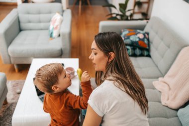 Küçük oğluyla oynayan mutlu orta yaşlı kadın. Onlar oynamak, öğrenmek ve çevrimiçi sörf yapmak için akıllı telefon ve dizüstü bilgisayar kullanıyorlar..