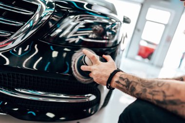 Modern bir araba atölyesinde profesyonel araç cilalama ve detay verme servisi. Parlak ışıklandırılmış çalışma alanı, büyük ışıklı. Yüksek kaliteli araba valelik kavramı.