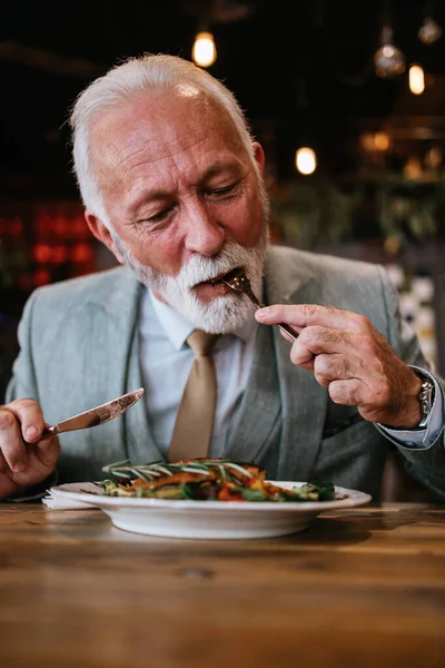 stock image Happy businessman sitting in restaurant and having lunch. He is enjoying in delicious food and wine.