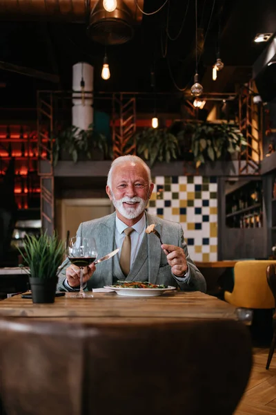 stock image Happy businessman sitting in restaurant and having lunch. He is enjoying in delicious food and wine.