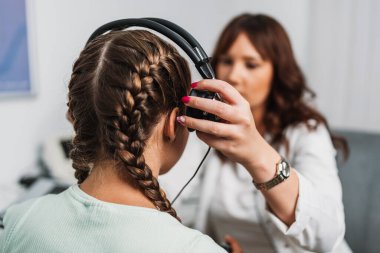 Odiyolog işitme güçlüğü teşhisi veya odiyometri yapıyor. Güzel bir genç kız işitme kliniğinde işitme testi yaptırıyor. Sağlık ve Tıp Konsepti.