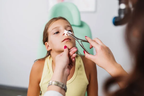 stock image Female audiologist examining girl ear using otoscope in doctors office. Child receiving a ear exam. Nose and throat medical examination. Healthcare and medicine concept. 