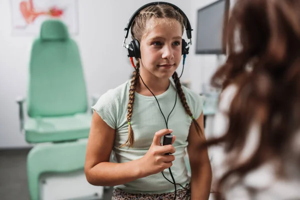 Audiologist doing impedance audiometry or diagnosis of hearing impairment. An beautiful teenage girl getting an auditory test at a hearing clinic. Healthcare and medicine concept.