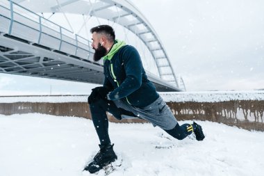 Çok soğuk ve karlı bir günde sakallı, koşan ve dışarıda egzersiz yapan yakışıklı orta yaşlı bir adam. Spor ve spor motivasyon teması.