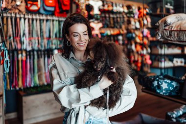 Güzel genç bir kadın, sevimli kahverengi oyuncak kanişiyle modern evcil hayvan dükkanında eğleniyor.. 