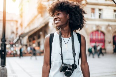 Genç siyah bayan turist güzel bir Avrupa şehrinin sokaklarında yürümekten zevk alıyor. O mutlu ve fotoğraf makinesini fantastik mimari fotoğraflar çekmek için kullanıyor. Parlak güneşli bir gün.