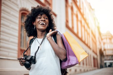 Genç siyah bayan turist güzel bir Avrupa şehrinin sokaklarında yürümekten zevk alıyor. O mutlu ve fotoğraf makinesini fantastik mimari fotoğraflar çekmek için kullanıyor. Parlak güneşli bir gün.