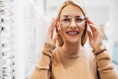 Modern optik mağazada gözlük çerçevesi seçen güzel ve şık bir kadın.. 