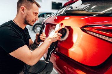 Modern bir araba atölyesinde profesyonel araç cilalama ve detay verme servisi. Parlak ışıklandırılmış çalışma alanı, büyük ışıklı. Yüksek kaliteli araba valelik kavramı.