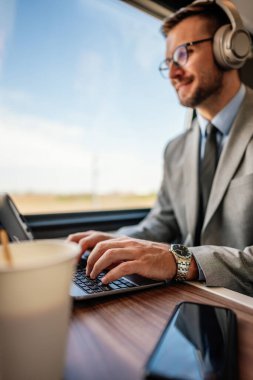 Yüksek hızlı trenle seyahat ederken dizüstü bilgisayar kullanarak zarif iş adamının ellerini yakın plan çek. Modern ve hızlı seyahat kavramı.