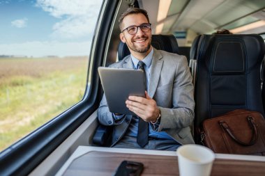 Hızlı trenle seyahat ederken dizüstü bilgisayarını kullanan orta yaşlı yakışıklı bir iş adamı. Modern ve hızlı seyahat kavramı.