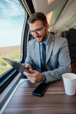 Hızlı trenle seyahat ederken dizüstü bilgisayarını kullanan orta yaşlı yakışıklı bir iş adamı. Modern ve hızlı seyahat kavramı.