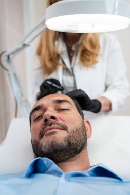 Yakışıklı orta yaşlı adam, saç kaybına karşı gelişmiş trombosit Rich PRP tedavisi görüyor. Erkekler için modern estetik tedaviler. Sağlık ve güzellik konsepti.